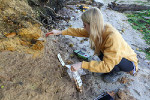 female geologist taking samples from a rock face